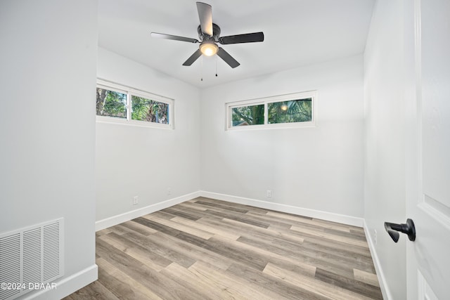 unfurnished room featuring wood finished floors, plenty of natural light, baseboards, and visible vents