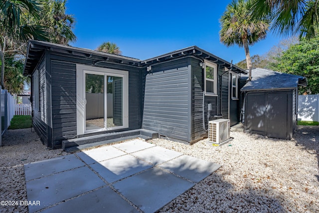 rear view of property featuring ac unit, fence, a shed, an outdoor structure, and a patio area