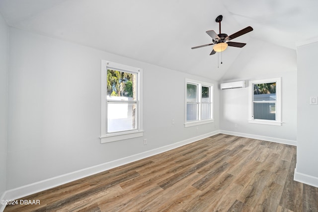 spare room with ceiling fan, baseboards, a wall unit AC, vaulted ceiling, and wood finished floors