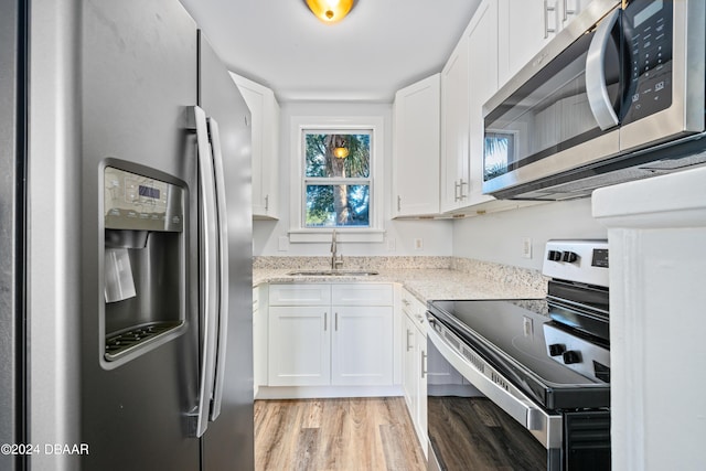 kitchen featuring light stone counters, white cabinets, appliances with stainless steel finishes, and a sink