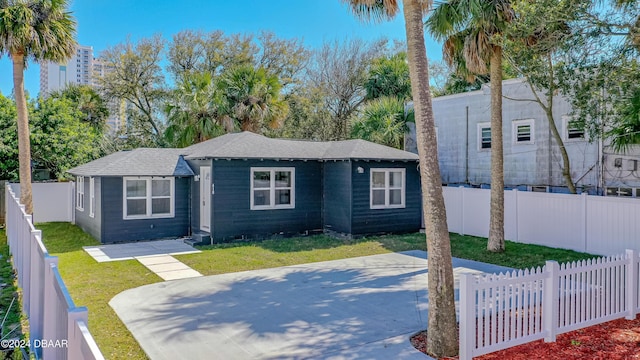 bungalow-style house featuring a fenced backyard, a front lawn, and roof with shingles