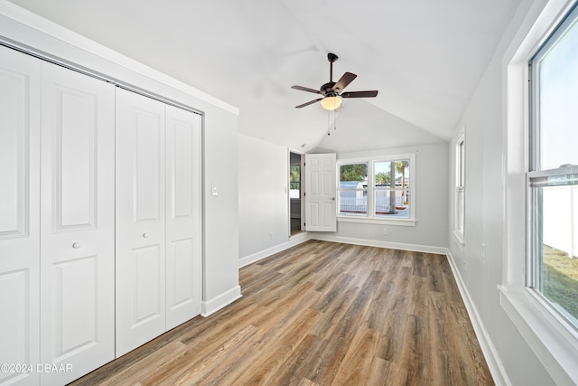 unfurnished bedroom featuring a ceiling fan, wood finished floors, baseboards, lofted ceiling, and a closet