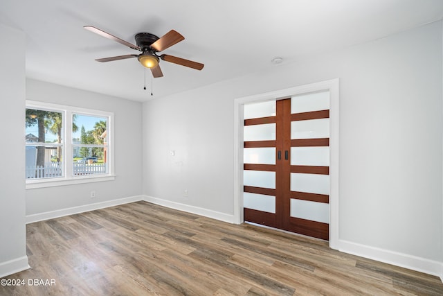 unfurnished room with ceiling fan, baseboards, and wood finished floors