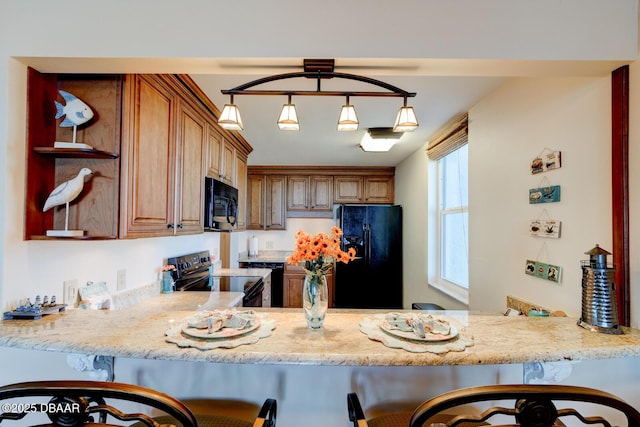 kitchen with a breakfast bar, decorative light fixtures, kitchen peninsula, light stone countertops, and black appliances