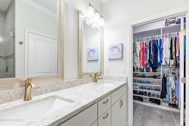 bathroom with hardwood / wood-style flooring, a shower with shower door, vanity, and ornamental molding