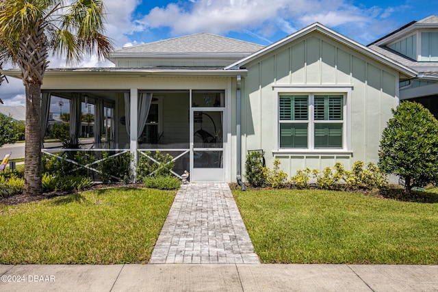 view of front of home featuring a sunroom and a front lawn