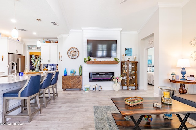 living room featuring a fireplace, ornamental molding, and light hardwood / wood-style flooring