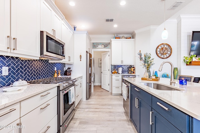 kitchen featuring stainless steel appliances, white cabinetry, sink, blue cabinets, and pendant lighting