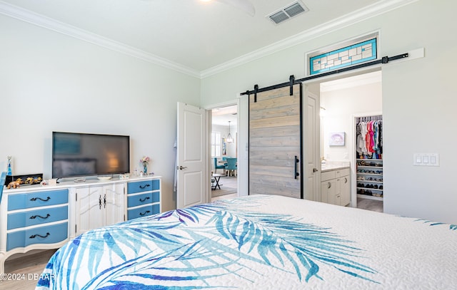 bedroom featuring a closet, ensuite bath, crown molding, a barn door, and light hardwood / wood-style flooring