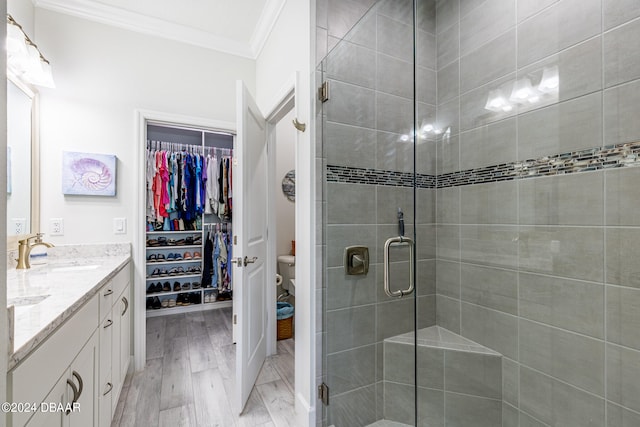 bathroom featuring ornamental molding, wood-type flooring, vanity, an enclosed shower, and toilet