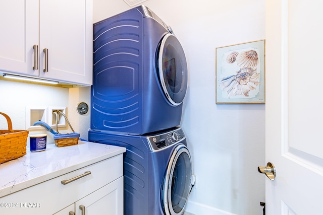 laundry area featuring cabinets and stacked washer / dryer