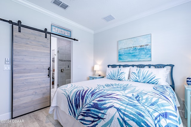 bedroom with a barn door, light hardwood / wood-style floors, connected bathroom, and crown molding