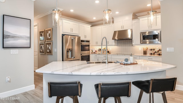 kitchen with white cabinetry, appliances with stainless steel finishes, pendant lighting, and light stone countertops