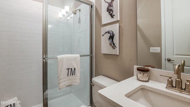 bathroom with toilet, vanity, and a shower with shower door