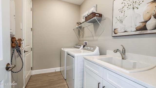 washroom with washer and clothes dryer, cabinets, sink, and light hardwood / wood-style floors