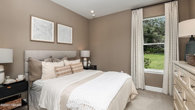 carpeted bedroom with a textured ceiling and multiple windows