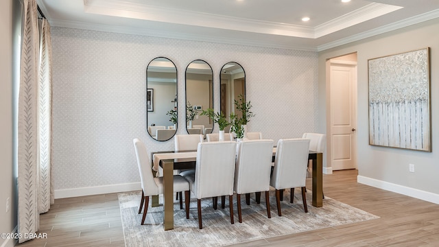 dining area with a raised ceiling, light hardwood / wood-style flooring, and crown molding