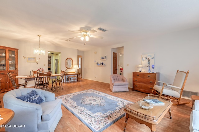 living room featuring light hardwood / wood-style floors and ceiling fan with notable chandelier