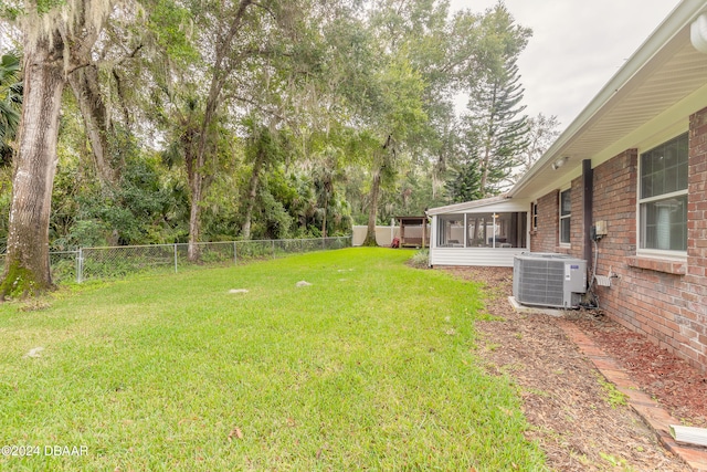 view of yard with central AC and a sunroom