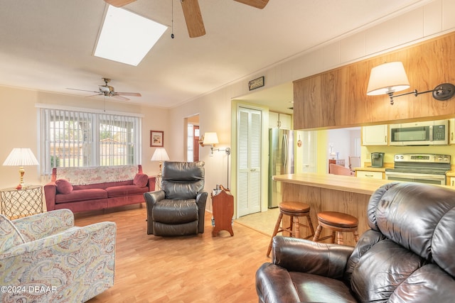 living room featuring a skylight, light hardwood / wood-style floors, and ornamental molding