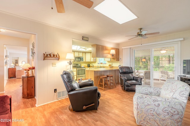 living room featuring light hardwood / wood-style floors and a skylight