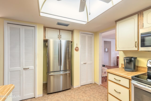 kitchen with ceiling fan, light tile patterned floors, cream cabinetry, and appliances with stainless steel finishes