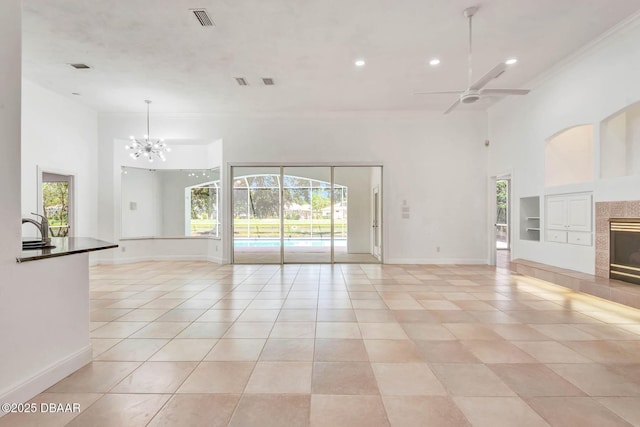 6062 Sabal Crossing Ct, Port Orange, FL 32128 - unfurnished living room featuring ceiling fan, plenty of natural light, a tiled fireplace, a chandelier, and a towering ceiling