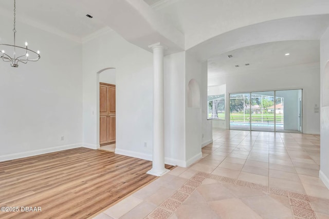 6062 Sabal Crossing Ct, Port Orange, FL 32128 - empty room featuring ornamental molding, arched walkways, baseboards, light tile patterned floors, and a chandelier