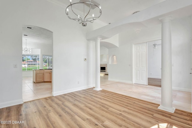 6062 Sabal Crossing Ct, Port Orange, FL 32128 - spare room featuring a chandelier, light wood-type flooring, a fireplace, and arched walkways