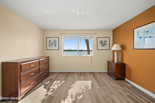 unfurnished bedroom with light wood-type flooring and a textured ceiling