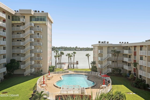 view of swimming pool with a water view and a lawn