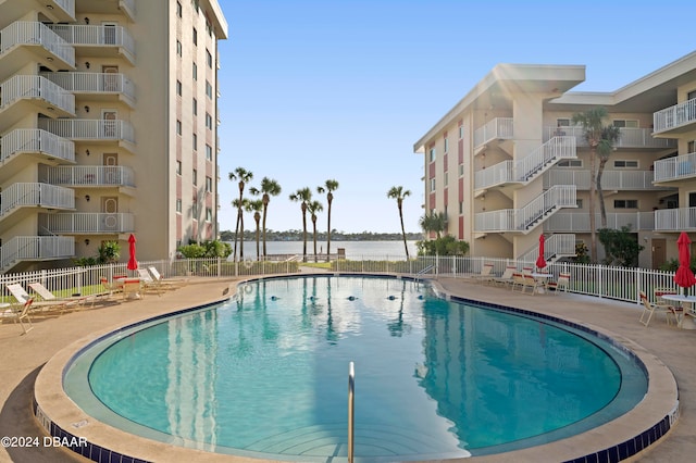 view of swimming pool with a patio area and a water view