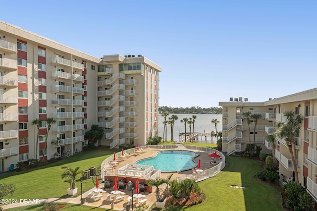 view of pool with a lawn, a patio, and a water view