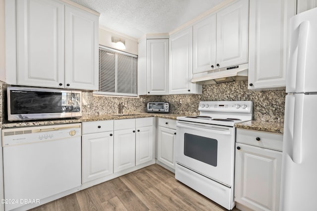 kitchen with white cabinets, a textured ceiling, stone counters, light hardwood / wood-style flooring, and white appliances