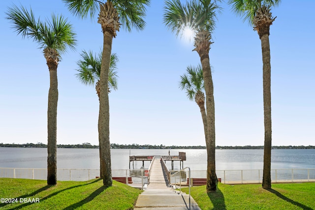 view of dock with a yard and a water view