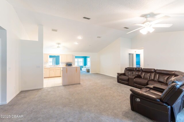 living room with ceiling fan, light colored carpet, and vaulted ceiling