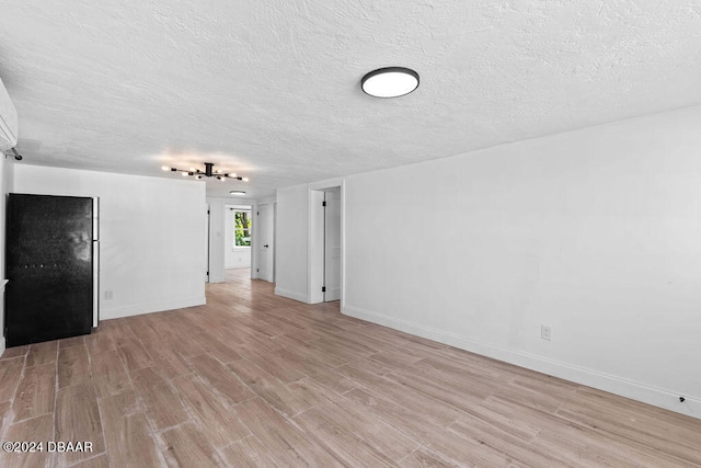 unfurnished living room featuring a textured ceiling and light hardwood / wood-style flooring