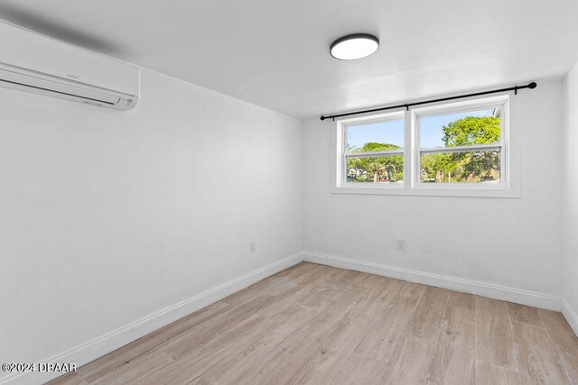 empty room with light wood-type flooring and a wall mounted air conditioner