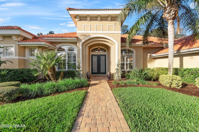 doorway to property featuring a yard, a tiled roof, and stucco siding