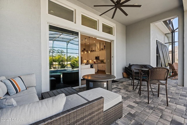 view of patio / terrace featuring outdoor lounge area, ceiling fan, and glass enclosure