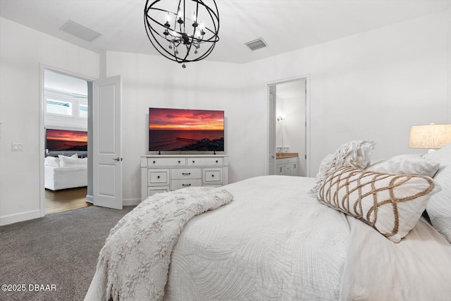 bedroom featuring ensuite bathroom, a chandelier, and dark colored carpet