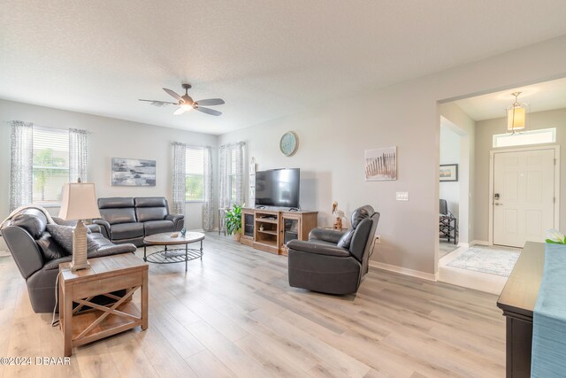 living room with light wood-type flooring, plenty of natural light, and baseboards