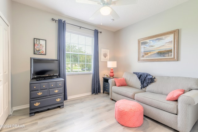 living area with baseboards, a ceiling fan, and light wood-style floors