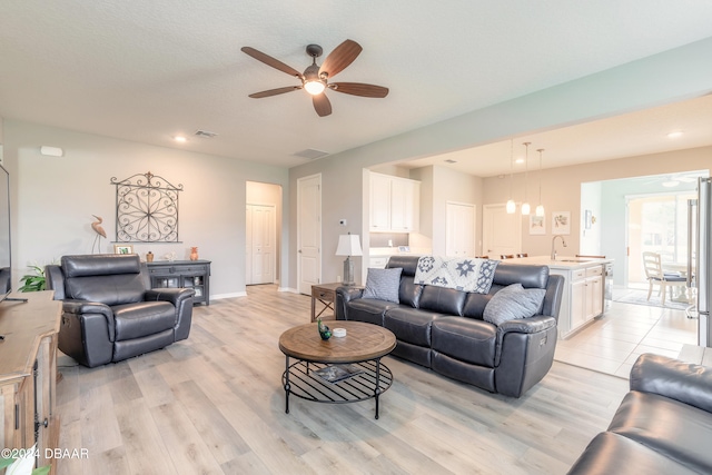 living room featuring ceiling fan, light wood-style flooring, and baseboards