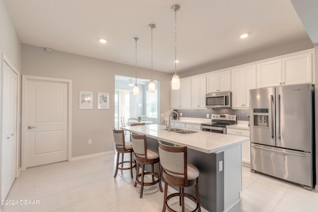 kitchen with a breakfast bar, light countertops, decorative backsplash, appliances with stainless steel finishes, and a sink