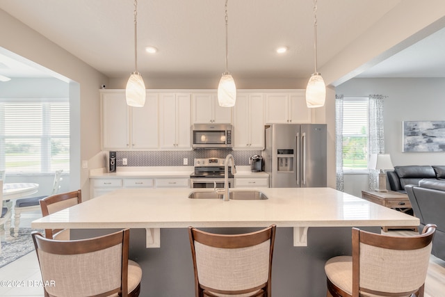 kitchen featuring white cabinets, decorative backsplash, open floor plan, stainless steel appliances, and a sink