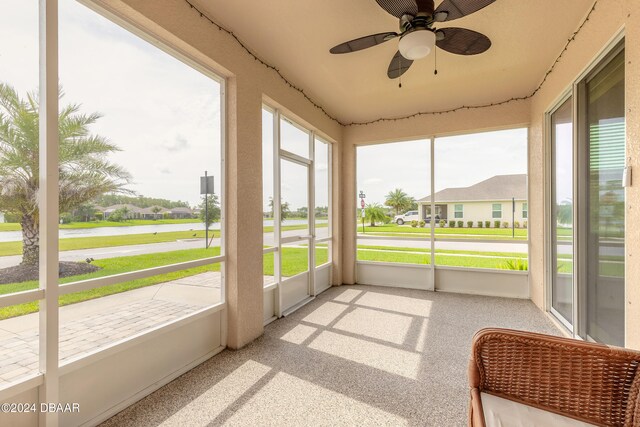 sunroom with a ceiling fan and a residential view