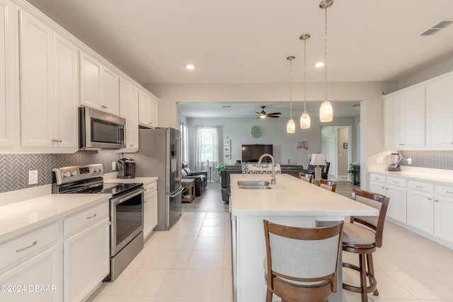 kitchen featuring stainless steel appliances, visible vents, open floor plan, white cabinetry, and a sink