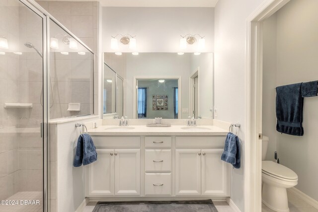 full bath featuring double vanity, a shower stall, toilet, and a sink