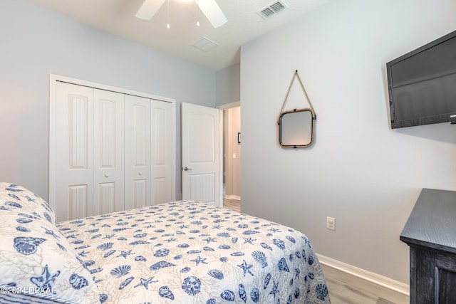 bedroom featuring a closet, visible vents, ceiling fan, wood finished floors, and baseboards